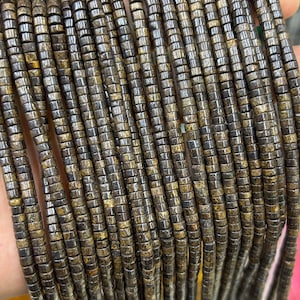 May include: A strand of brown and gold cylindrical beads. The beads are made of natural materials and have a rough, textured surface.