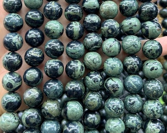 Puede incluir: Una hebra de cuentas redondas con patrones verdes y negros. Las cuentas están hechas de piedra natural con un aspecto marmoleado.