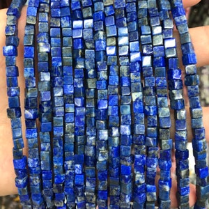 May include: A strand of blue lapis lazuli gemstone beads, each bead is a square cube shape.