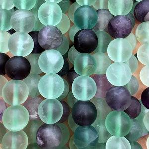 May include: A strand of round, frosted fluorite beads in shades of green, purple, and black. The beads are approximately 8mm in diameter.