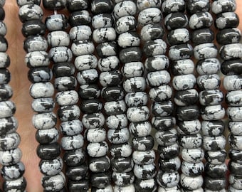 May include: A strand of black and white snowflake obsidian beads. The beads are round and have a speckled pattern.