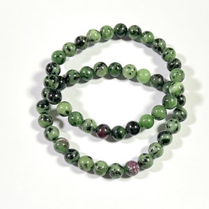 Puede incluir: Dos pulseras de piedras preciosas verdes y negras con pequeñas cuentas redondas.