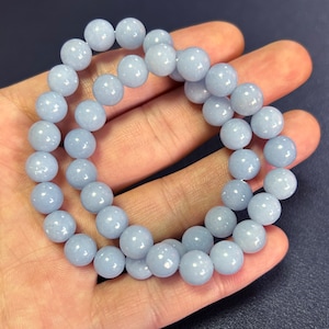 Könnte beinhalten: Ein hellblaues Edelstein-Armband mit runden Perlen. Das Armband besteht aus natürlichen Steinen und ist etwa 20 cm lang.