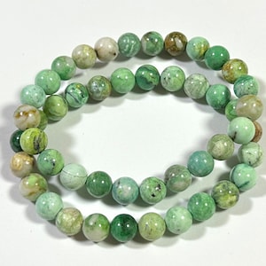 May include: A green and white gemstone bracelet with round beads. The beads have a mottled pattern.