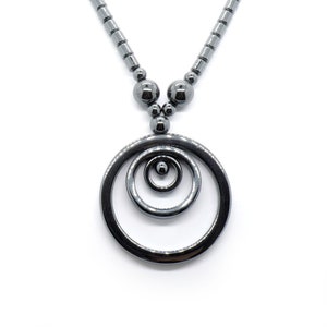 May include: A black hematite necklace with a pendant featuring three concentric circles.