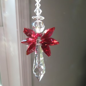 May include: A crystal suncatcher with a red crystal flower design. The suncatcher is hanging from a clear crystal chain.