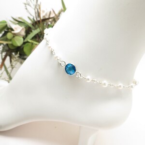 May include: A silver anklet with a blue gemstone and white pearl accents.