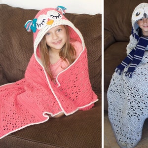 May include: Two children wearing crocheted owl hooded blankets. The girl's blanket is pink with a white trim and the boy's blanket is gray with a blue and white striped scarf.