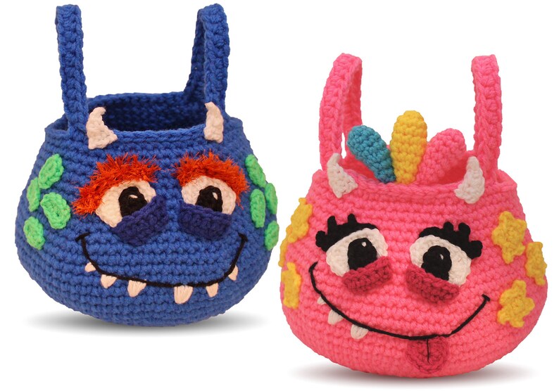 May include: Two crocheted monster-shaped baskets with handles. One is blue with green and orange details, the other is pink with yellow and blue details.