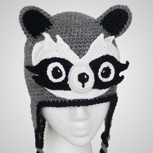 May include: Gray crocheted hat with black and white raccoon face details. The hat has long ear flaps and a black crocheted brim.