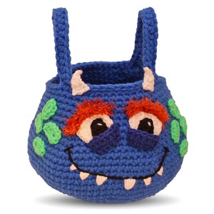 May include: Blue crocheted monster-shaped basket with green spots, orange hair, and white teeth. The basket has two blue handles.