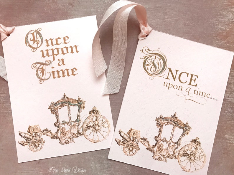 May include: Two pink cards with gold lettering and illustrations of a horse-drawn carriage. The text on the cards reads "Once upon a time".