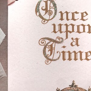 May include: A pink card with the words "Once upon a time" written in gold script with glitter accents.