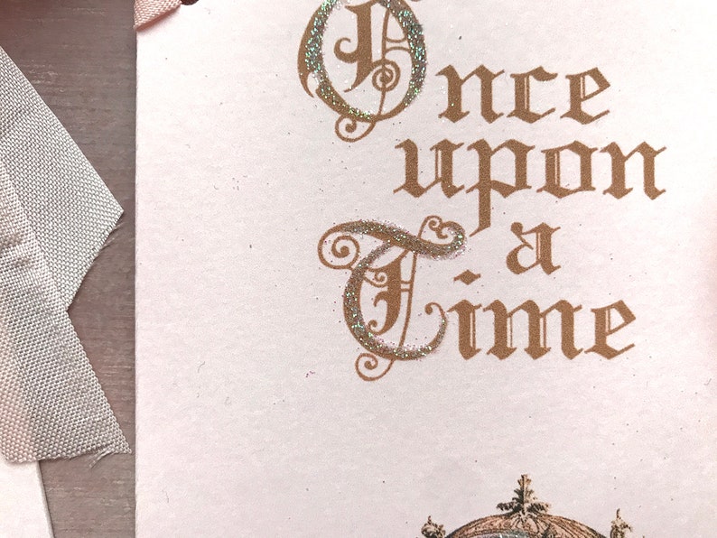 May include: A pink card with the words "Once upon a time" written in gold script with glitter accents.