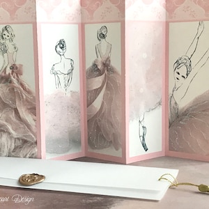 May include: A pink and white card with a ballerina illustration on each panel. The card is folded into a concertina style and has a white envelope with a gold wax seal. The envelope has a gold tassel attached.