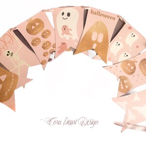 May include: A decorative bunting banner featuring a series of light pink pennants strung together with ribbon. The pennants display various Halloween-themed illustrations in gold and white, including pumpkins, ghosts, a skeleton, and the text BOO and halloween.