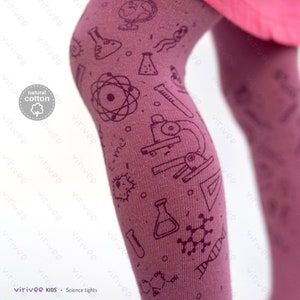 May include: Dark mauve tights featuring a repeating dark purple print of scientific icons including a microscope, atom, test tubes, beakers, DNA strands, and the equation E=mc2. A circular badge on the side displays the text natural cotton.