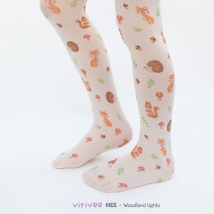 May include: White tights with a woodland animal print featuring squirrels, hedgehogs, mushrooms, and acorns. The tights are sheer and have a subtle sheen.