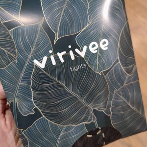 May include: A dark green and gold packaging with a leafy pattern for Virivee tights.