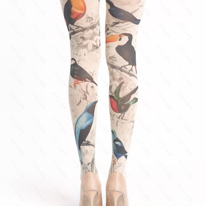 May include: A pair of beige tights with a bird print design. The tights feature toucans, bluebirds, and other birds on a white background. The text "virivee TIGHTS" is printed on the tights.