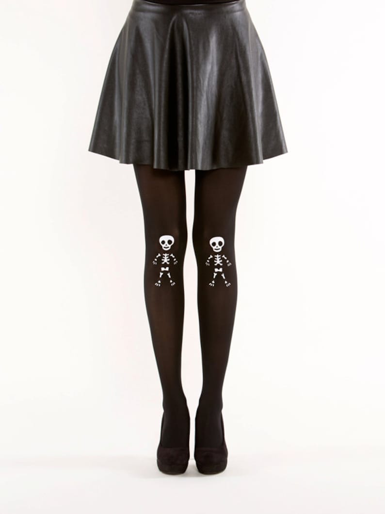 May include: Black opaque tights with white skeleton designs on the lower legs. The tights are paired with a black leather skirt.