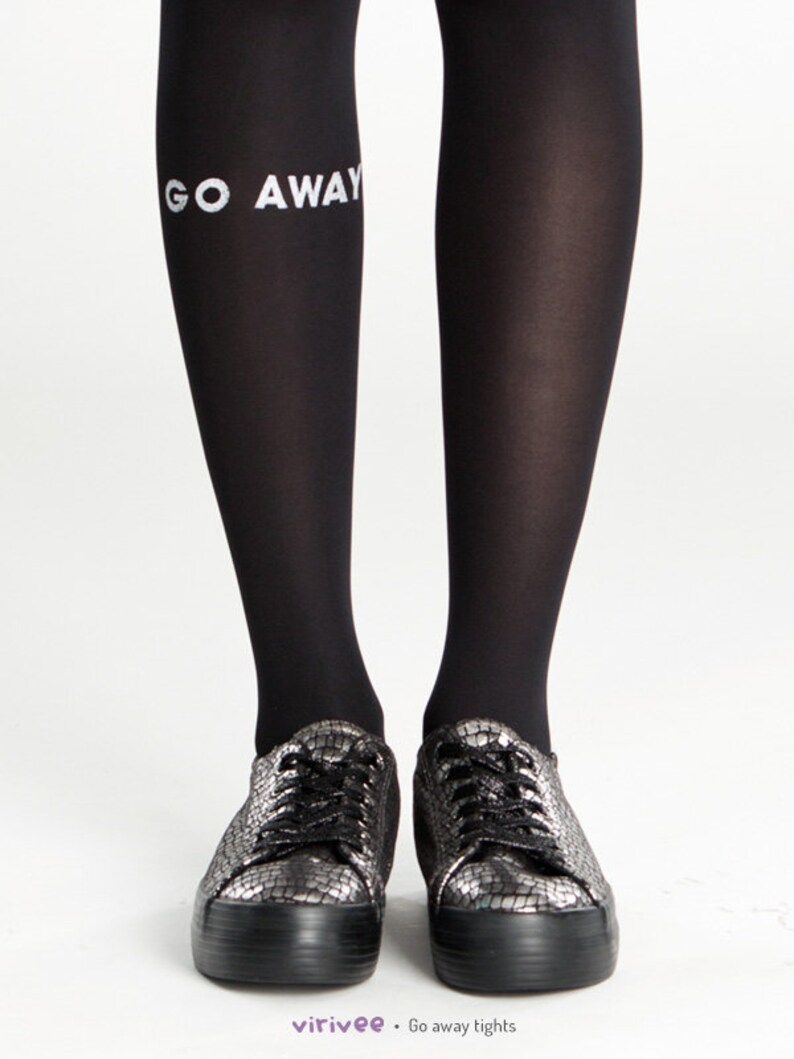 Peut inclure: Collants noirs avec l'inscription "GO AWAY" imprim&eacute;e sur la jambe gauche. Le mannequin porte des baskets noires et argent&eacute;es.