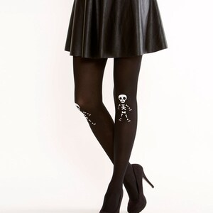 May include: Black opaque tights with a white skeleton design on the legs. The tights are paired with a black leather skirt and black high heels.