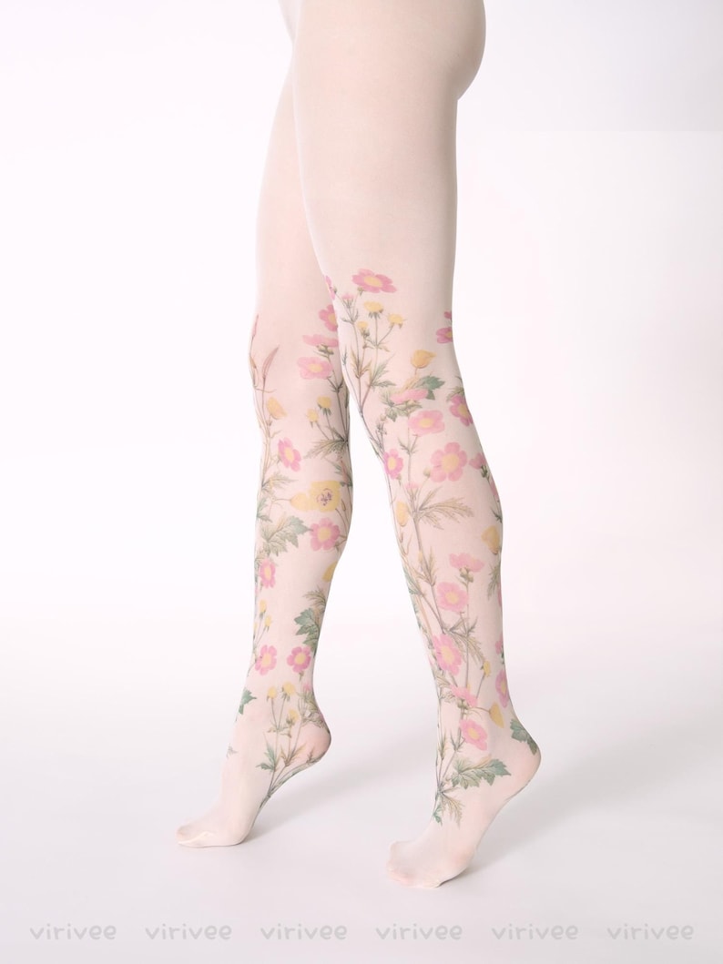 Op de afbeelding: Transparante witte panty met een botanische print van roze en gele wilde bloemen met groene stengels en bladeren. Het bloemmotief loopt van de enkels tot aan de dijen en bedekt de benen met een delicaat, op de natuur ge&iuml;nspireerd ontwerp.
