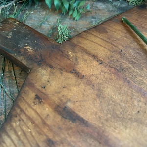 Pode incluir: Uma t&aacute;bua de corte de madeira r&uacute;stica com uma pega. A t&aacute;bua tem uma cor castanha quente com &aacute;reas mais escuras e gr&atilde;o de madeira vis&iacute;vel. Uma haste verde est&aacute; no lado direito. Para a prepara&ccedil;&atilde;o de alimentos.