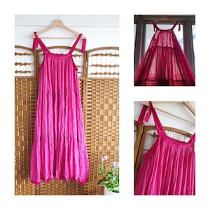 Puede incluir: Un vestido maxi rosa con volantes y tirantes finos. El vestido está hecho de una tela suave y fluida y tiene un corte holgado.