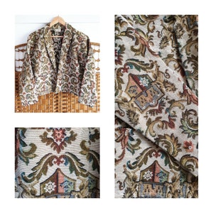 Op de afbeelding: Een vintage tapijtblazer met een bloemenpatroon in tinten bruin, groen en blauw. De blazer heeft een cropped pasvorm en een shawlkraag.