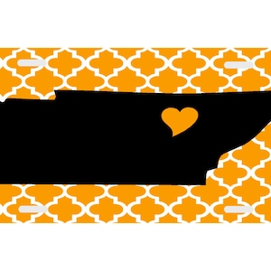 May include: Orange and white patterned license plate with a black silhouette of the state of Tennessee with a yellow heart in the center.