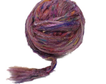 May include: A ball of colorful silk fibers in shades of purple, pink, blue, and green. The fibers are loosely spun and have a soft, fluffy texture.