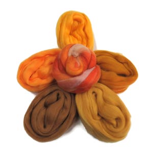 May include: Five balls of wool in shades of orange, yellow, and brown. The balls are arranged in a flower shape.