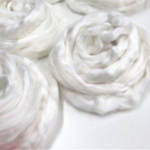 May include: White cotton balls arranged in a spiral shape, resembling a flower. The cotton balls are soft and fluffy, and they are arranged in a way that creates a sense of movement and texture.