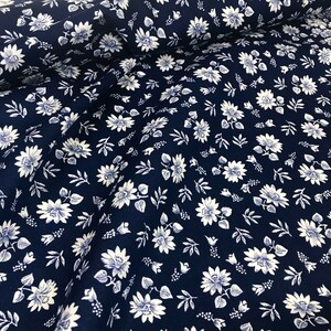 Puede incluir: Una tela azul marino con un patr&oacute;n floral blanco. La tela est&aacute; doblada por la mitad y el patr&oacute;n es visible en ambos lados.