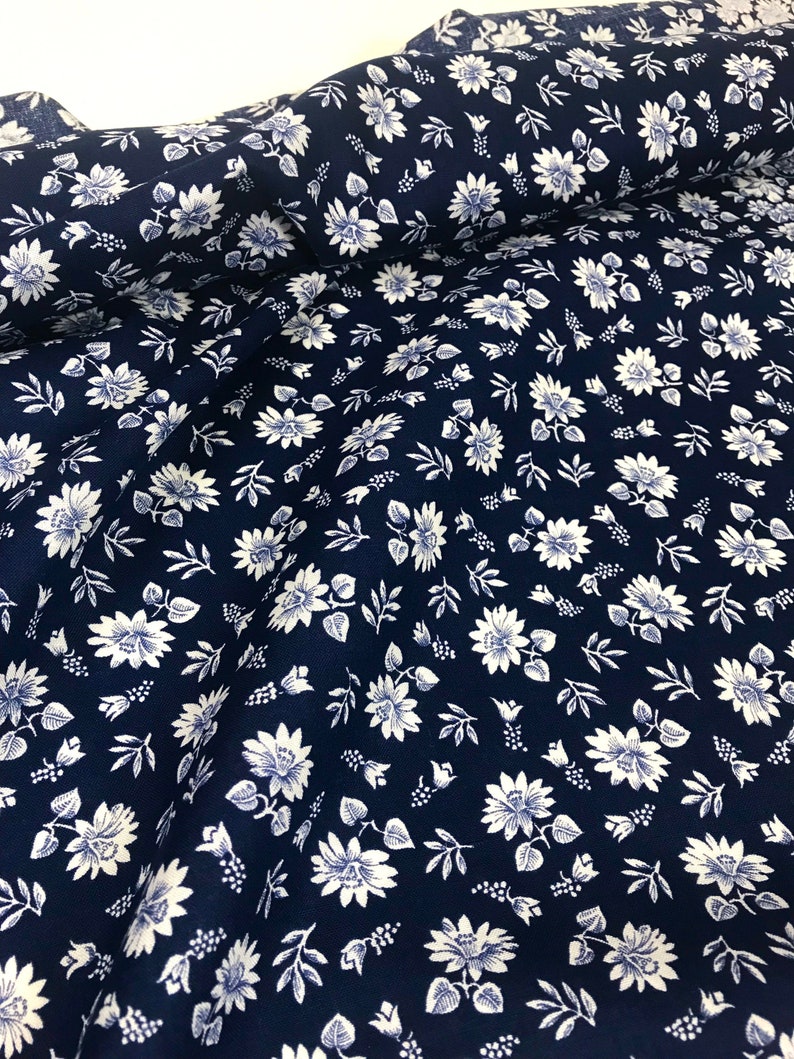 Puede incluir: Una tela azul marino con un patr&oacute;n floral blanco. La tela est&aacute; doblada por la mitad y el patr&oacute;n es visible en ambos lados.