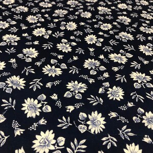 Puede incluir: Una tela azul marino con un patr&oacute;n floral blanco. El patr&oacute;n presenta peque&ntilde;as flores blancas con un centro azul y hojas.