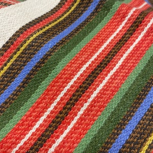 May include: Close-up of a woven fabric with stripes of red, white, green, blue, brown, and yellow.