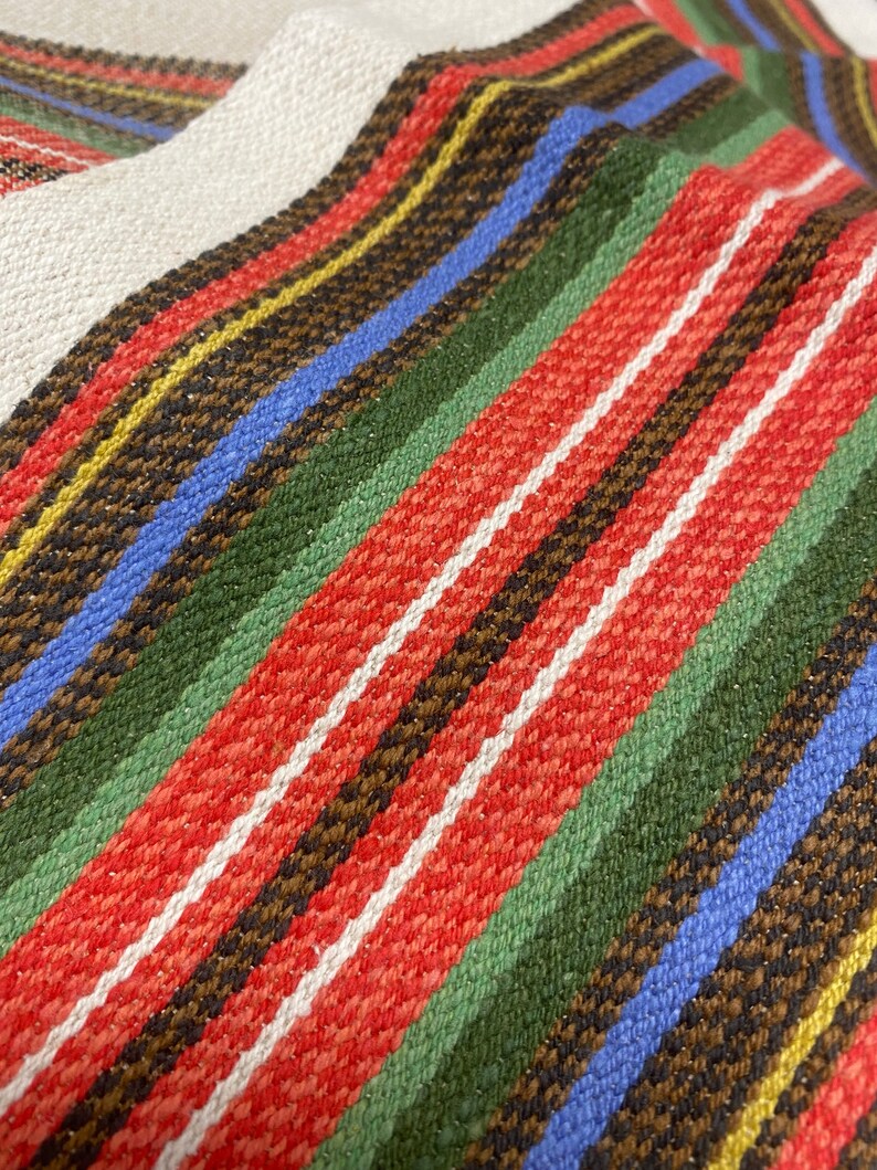 May include: Close-up of a woven fabric with stripes of red, white, green, blue, brown, and yellow.