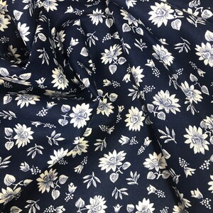 Puede incluir: Tela azul marino con un patr&oacute;n floral blanco. La tela es texturizada y tiene un brillo sutil.