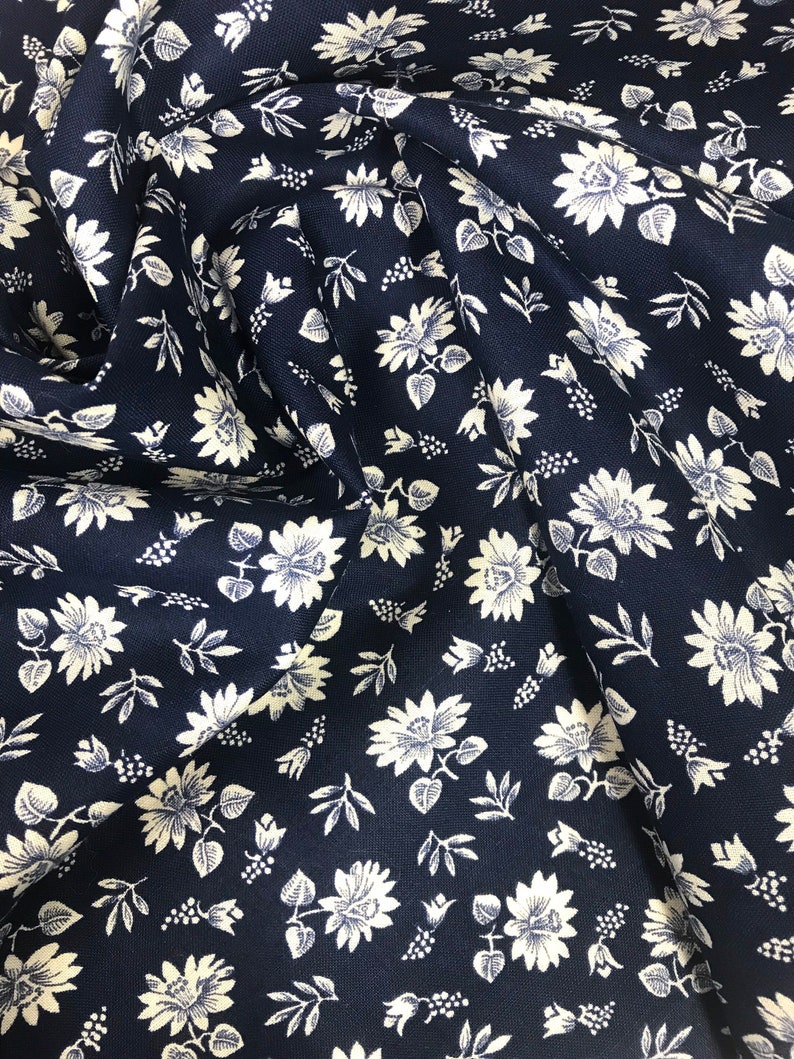 Puede incluir: Tela azul marino con un patr&oacute;n floral blanco. La tela es texturizada y tiene un brillo sutil.
