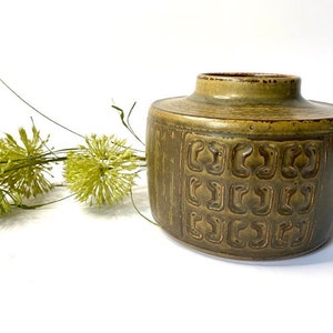 Peut inclure: Un vase en céramique vert avec un motif géométrique. Le vase a une forme arrondie et une large ouverture.