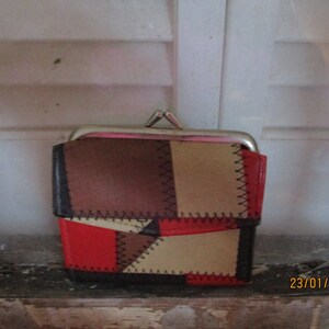 May include: A small, red, brown, and beige patchwork coin purse with a silver clasp.