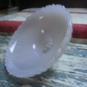 May include: A white glass lampshade with a scalloped edge. The lampshade is made of a translucent material and has a delicate, feminine look.