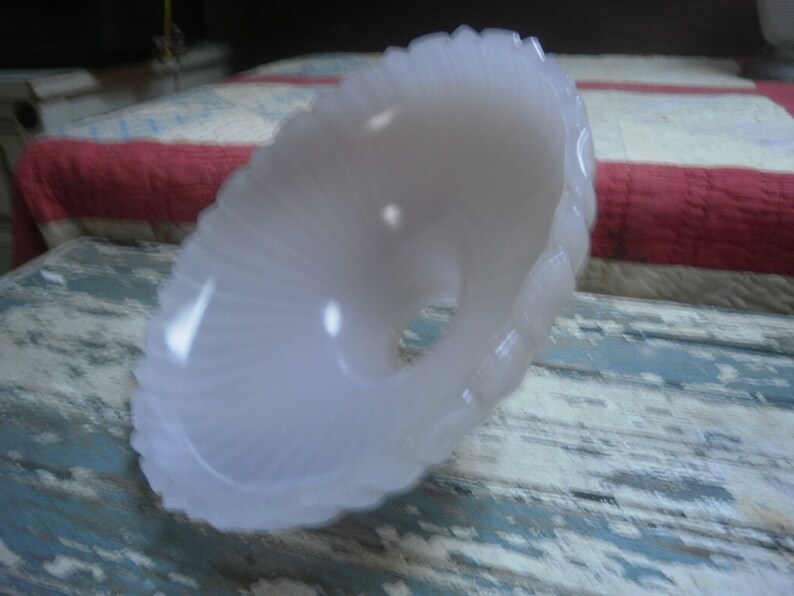 May include: A white glass lampshade with a scalloped edge. The lampshade is made of a translucent material and has a delicate, feminine look.
