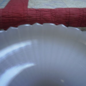 May include: A white, fluted, glass bowl with a scalloped edge.