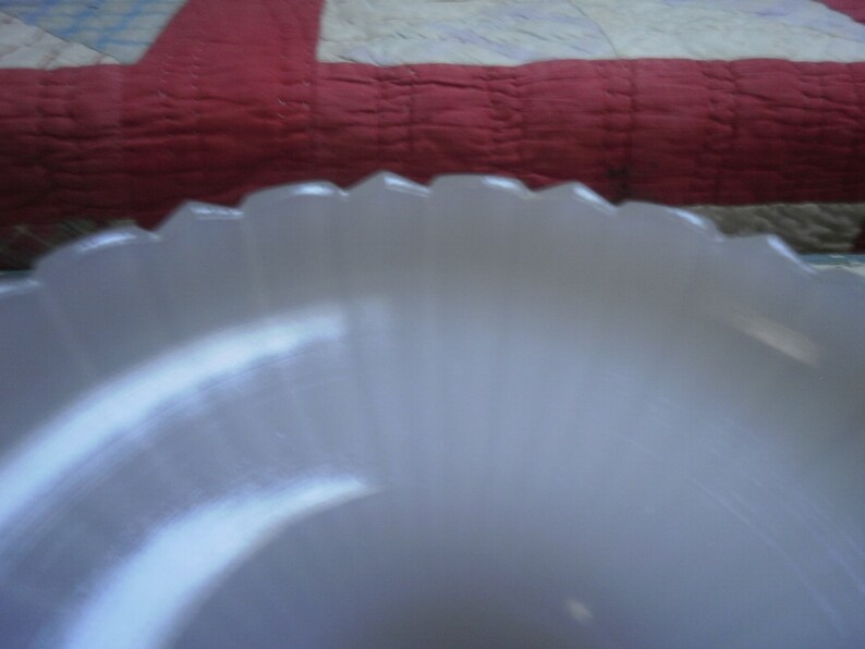 May include: A white, fluted, glass bowl with a scalloped edge.