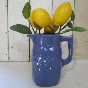 Red Clay Pottery Pitcher, Glazed with Blue, Pitcher has Fruit Designs on both sides, Stands 7 inches tall. Pretty Country Blue Color.