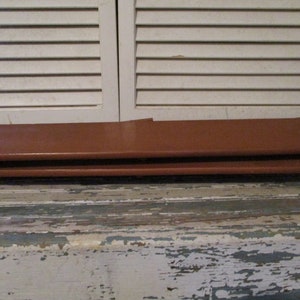 May include: Two brown leather-like rectangular pieces stacked on top of each other. The pieces are smooth and have a slight sheen.